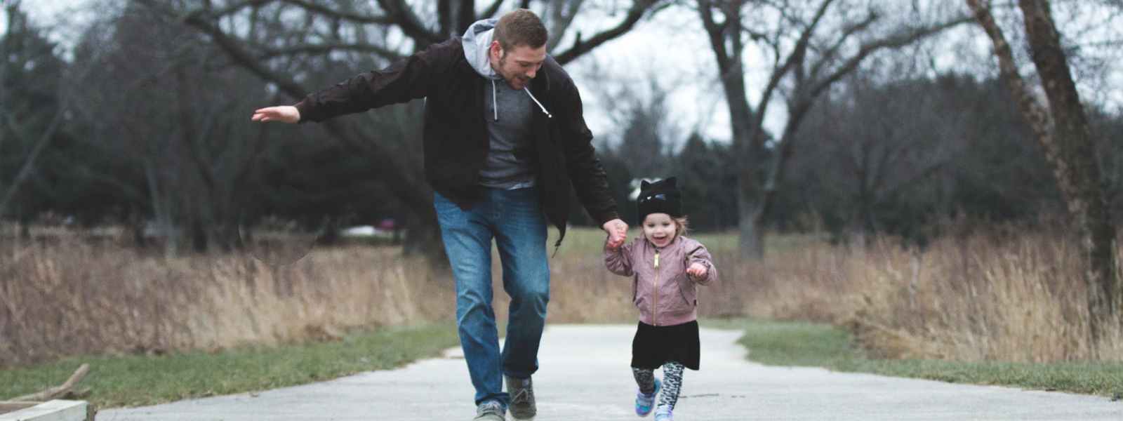 man and girl running on asphalt road