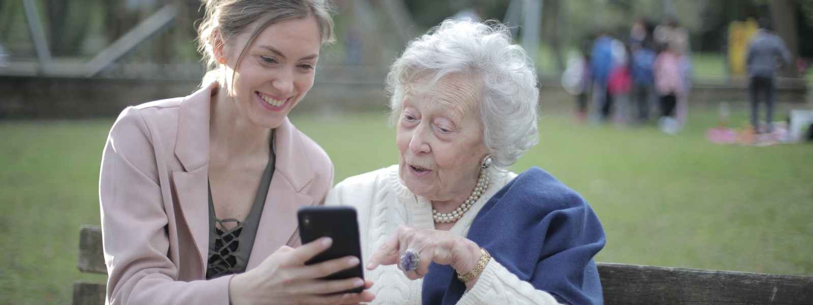 cheerful senior mother and adult daughter using smartphone together