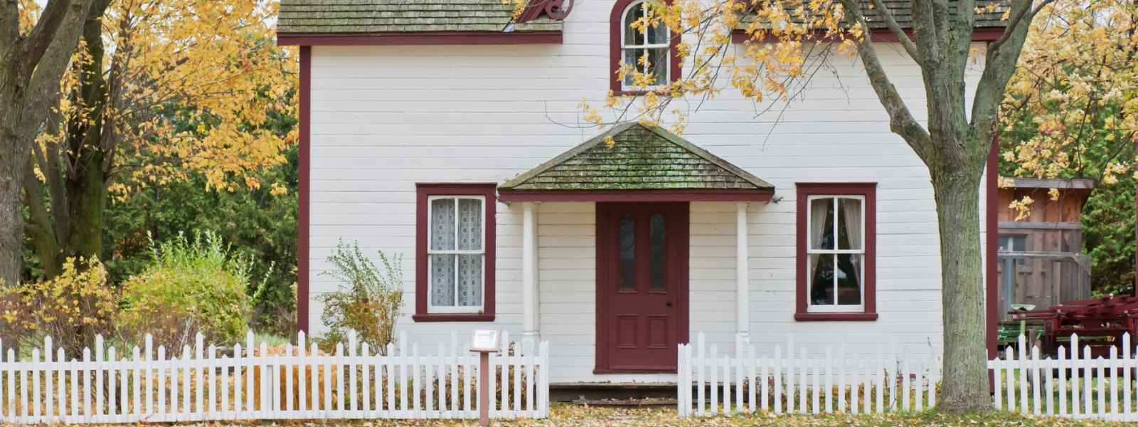 white and red wooden house with fence