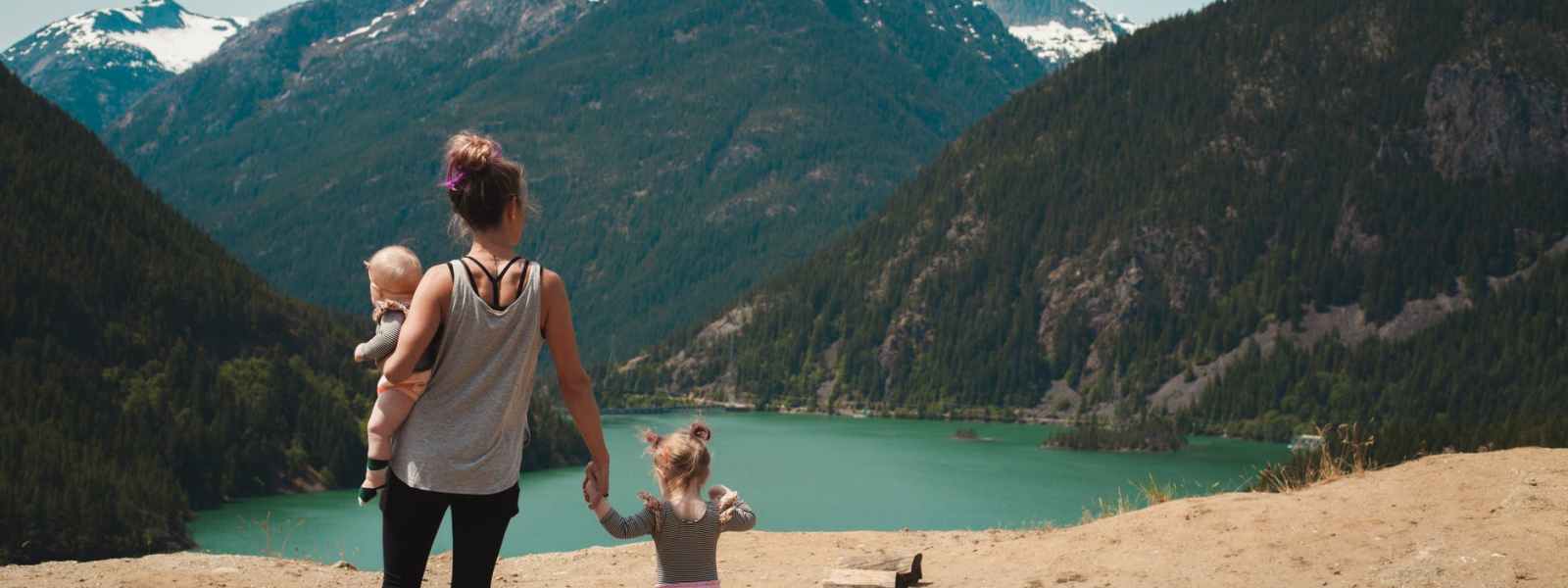 mother and children walks near body of water
