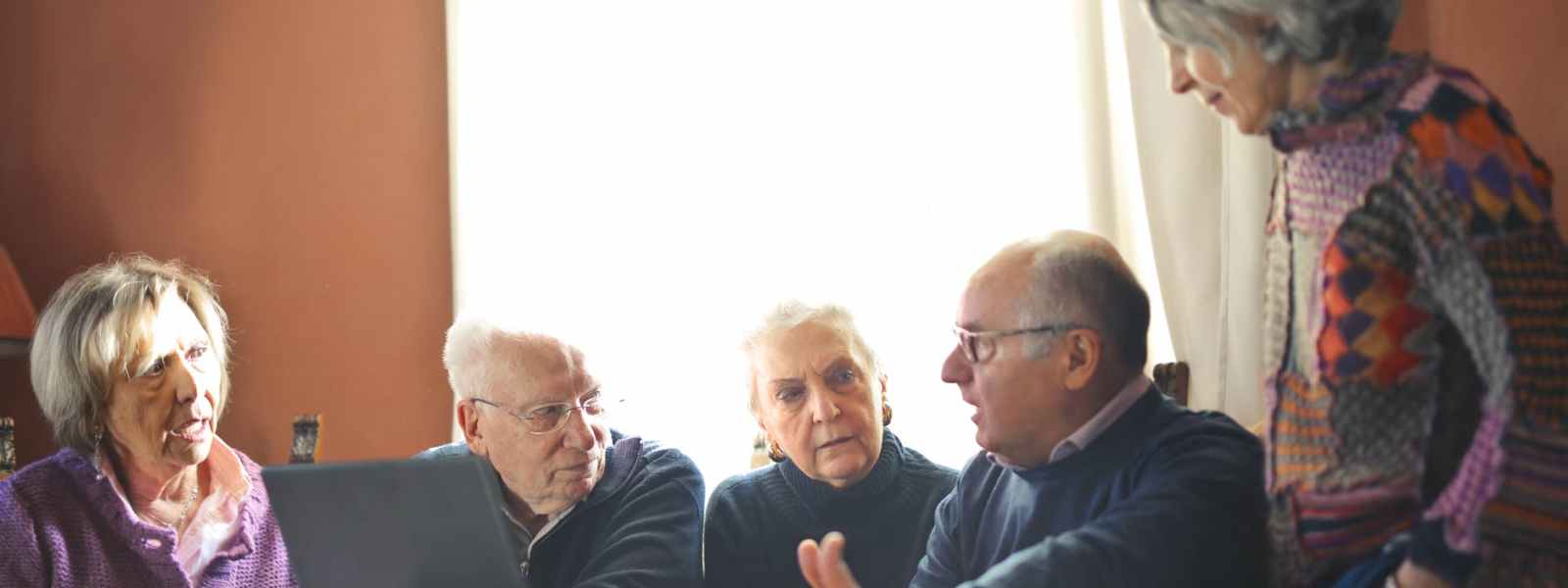 elderly people sitting at table with laptop