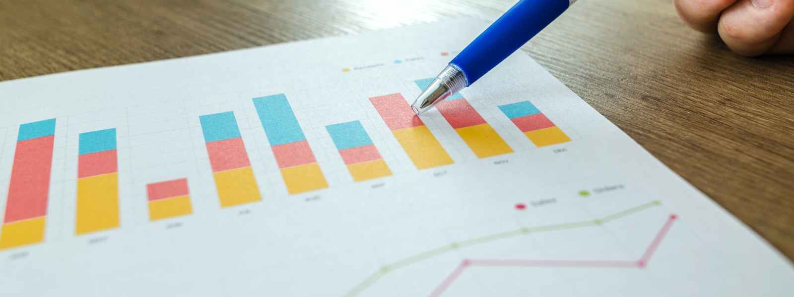 person holding pen pointing at graph