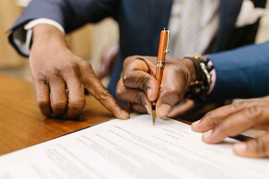 close up shot of a person writing on a contract