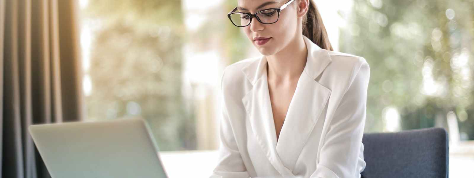 concentrated female entrepreneur typing on laptop in workplace