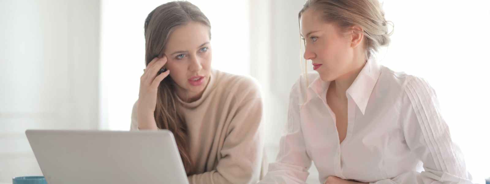 thoughtful businesswomen discussing problems in bright workspace