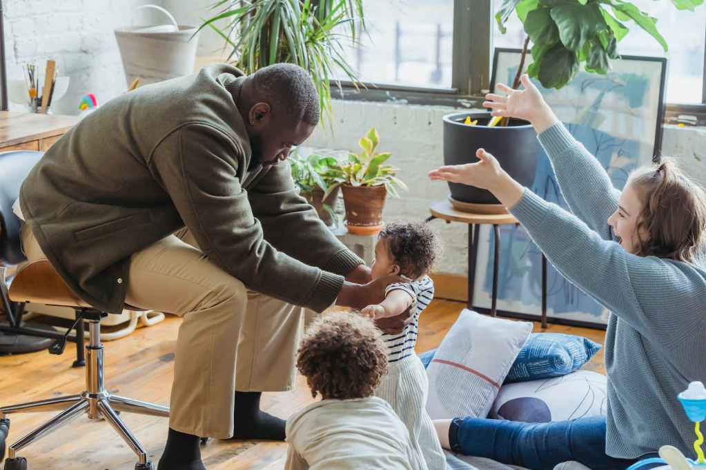 happy mother rejoicing first step of black baby with family