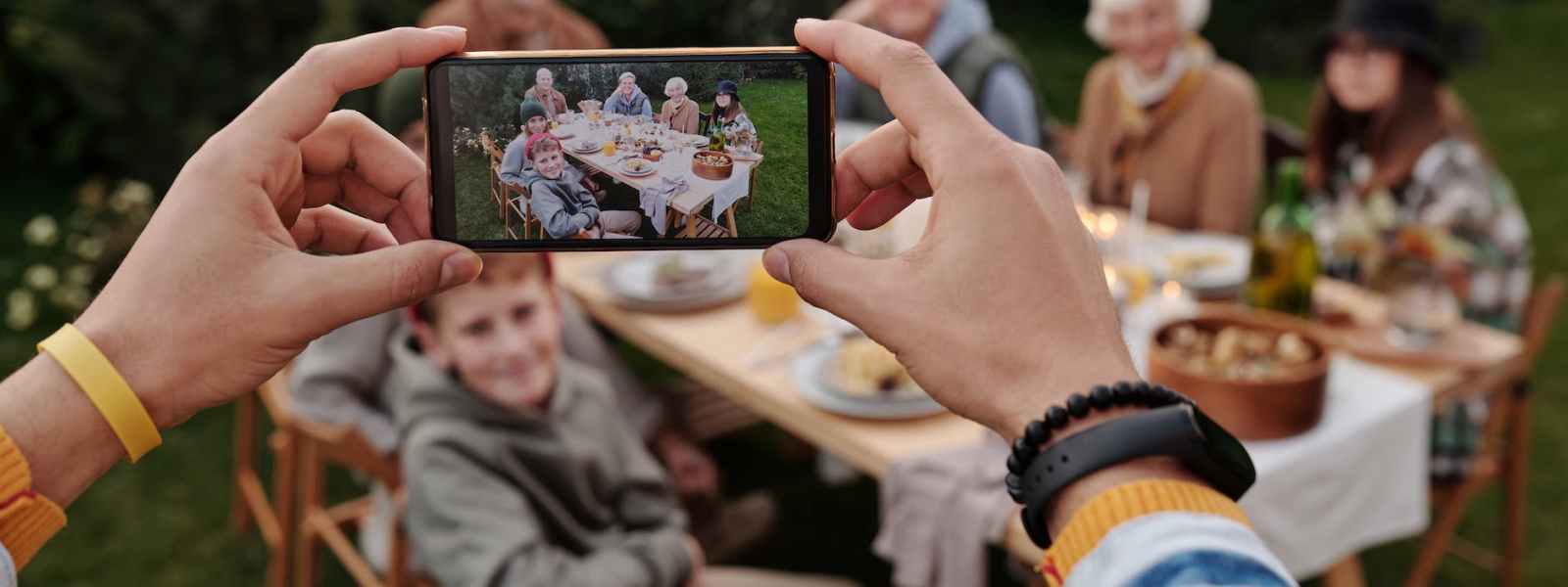 unrecognizable person taking photo of family dinner on smartphone