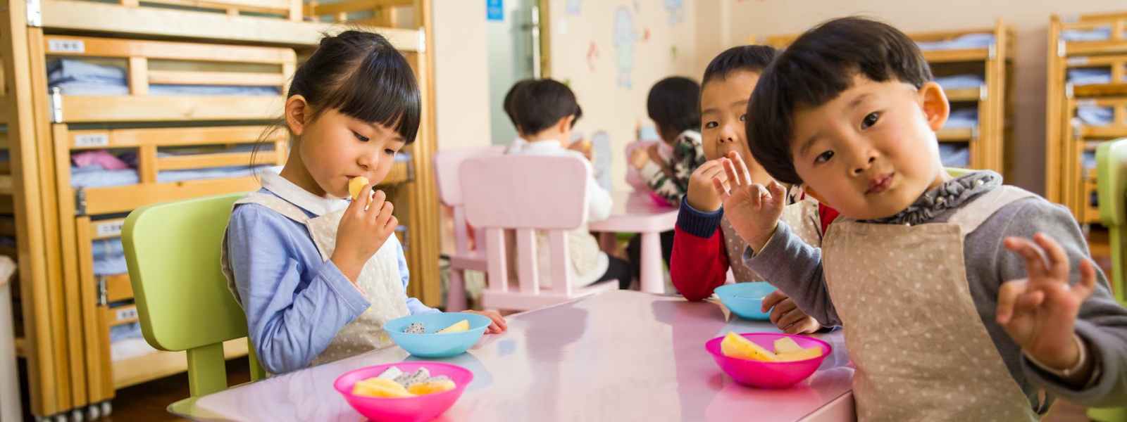 three toddler eating on white table