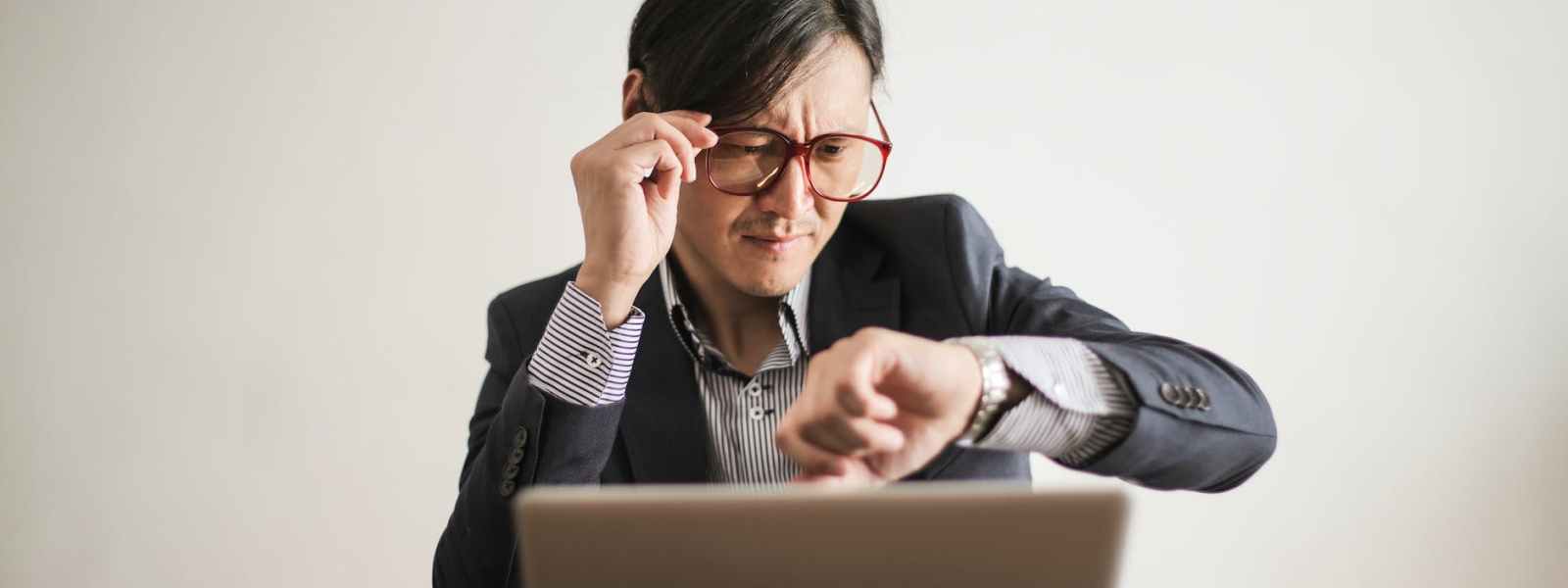 confused businessman checking time on wristwatch