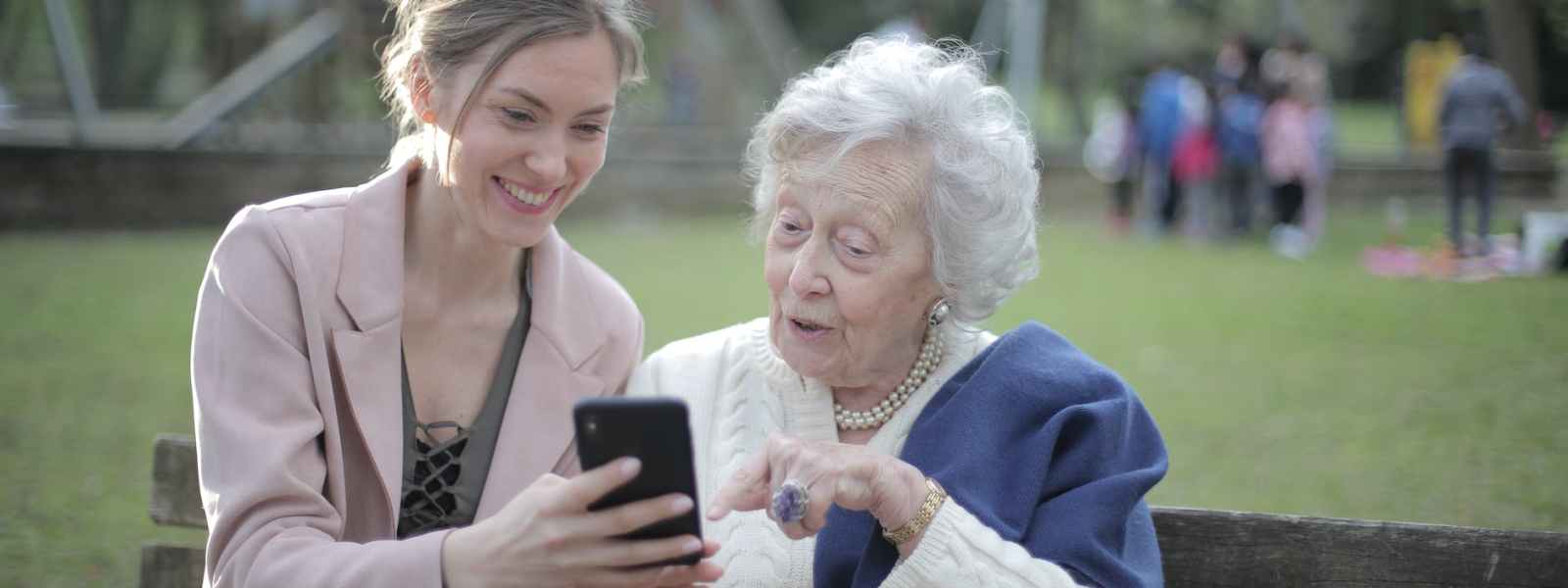 cheerful senior mother and adult daughter using smartphone together