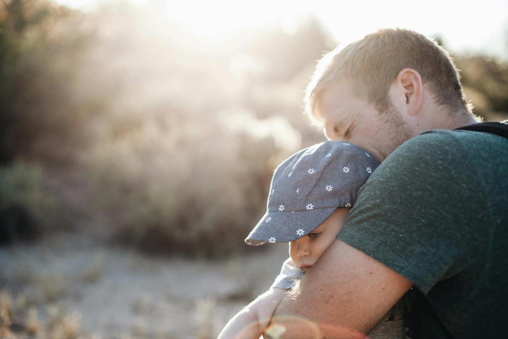 a man hugging his baby on a sunny afternoon