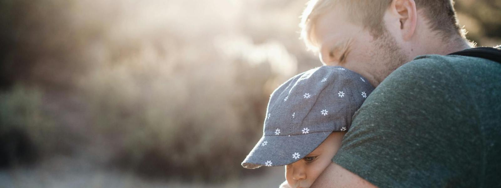 a man hugging his baby on a sunny afternoon